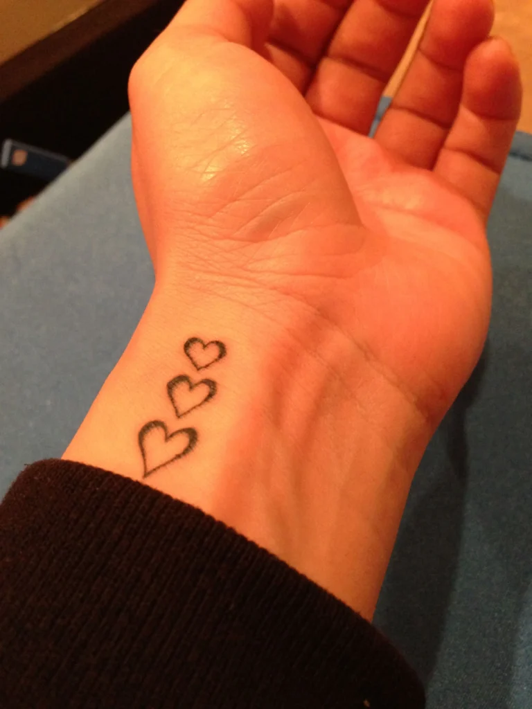 Tiny couple tattoo ideas with matching heart symbol on wrist
