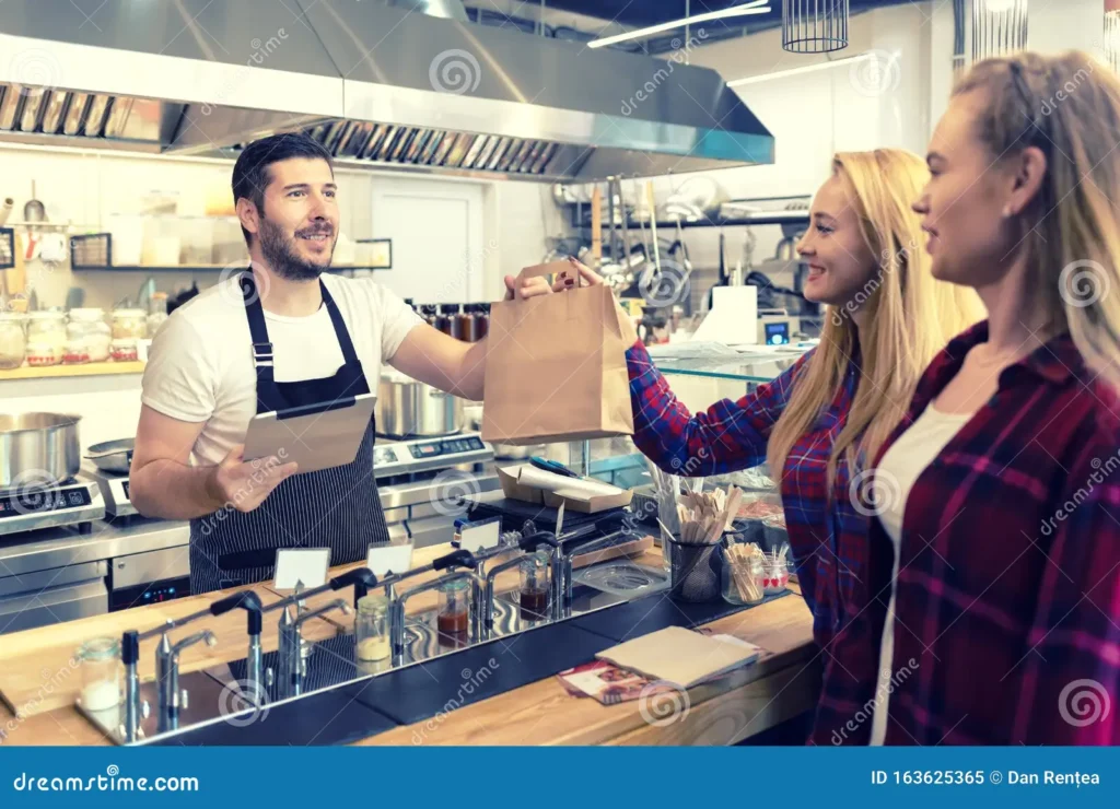 Restaurant staff serving a customer at the counter, related to the service and staff category of TellPopeyes survey questions
